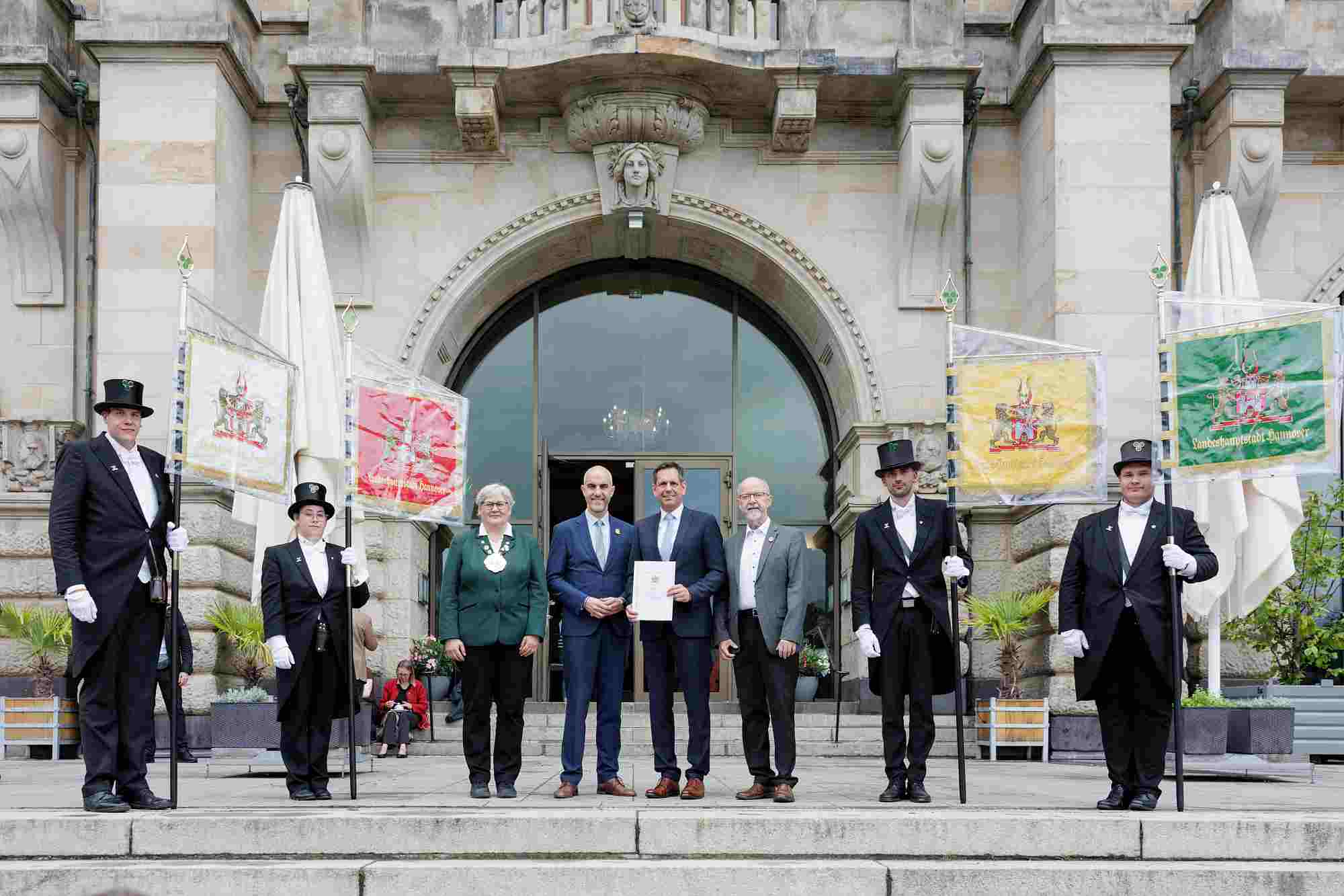 Schützenfest 2026 Auf dem Bild sind offizielle Vertreter der Stadt Hannover und des Schützenwesens vor dem Neuen Rathaus in Hannover zu sehen. Belit Onay (Zweiter von links in der Kerngruppe), der Oberbürgermeister der Landeshauptstadt Hannover sowie weitere Würdenträger der Stadt und Vertreter des Schützenpräsidiums, erkennbar an der traditionellen grünen Schützenjacke mit Schützenkette.